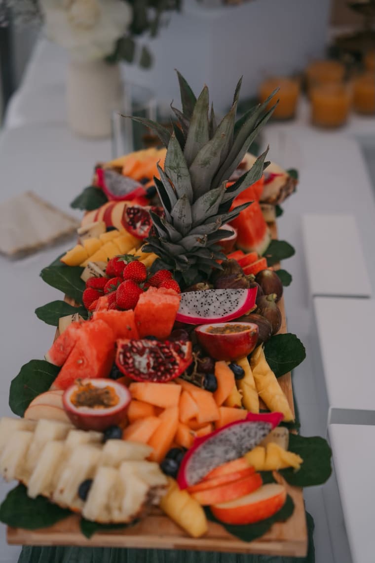 Plateau de fruits frais sur planche de bois : ananas, pastèque, grenade, fruit du dragon et fruits de la passion